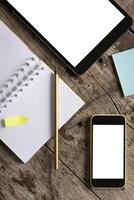 Tablet, Telefon und Notizblock auf Holztisch foto