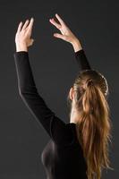 Ballerina-Tänzerin, die mit ihren Händen auf einem dunklen Hintergrund aufwirft