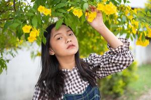 Portrait junges Mädchen mit gelben Blüten, Asiatin. foto