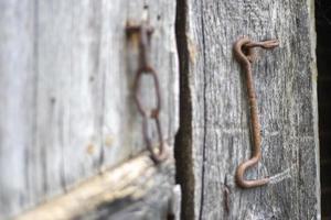 isolierte alte rostige Türklinke an einer Holztür. Nahansicht. problematische verwitterte Platten. alte Wand Textur Hintergrund. Detail einer alten Holztür mit einem rostigen Türriegel. foto