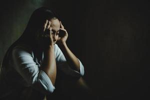 Frau traurig, Stress und Einsamkeit in einem dunklen Raum sitzend, unglückliches und weinendes Teenager-Mädchen vor häuslicher Gewalt, eine erwachsene Frau drückt Gefühle der Verzweiflung, Angst vor Belästigung aus.