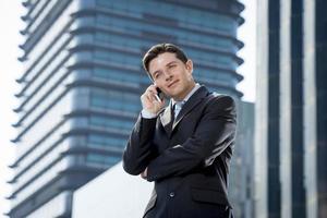 attraktiver Geschäftsmann in Anzug und Krawatte, der auf Handy spricht foto