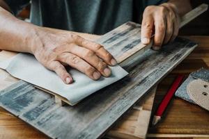 tischler verwenden trockenes schleifpapier zum polieren von holz in der werkstatt, im heimwerker- und holzbearbeitungskonzept. selektiver Fokus foto