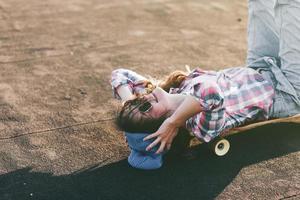 Mädchen mit Hut liegt auf Skateboard, foto