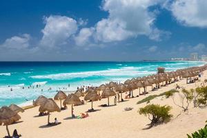 Regenschirme an einem Sandstrand mit azurblauem Wasser an einem sonnigen Tag in der Nähe von Cancun, Mexiko foto