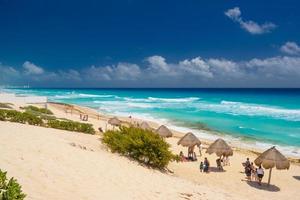 Regenschirme an einem Sandstrand mit azurblauem Wasser an einem sonnigen Tag in der Nähe von Cancun, Mexiko foto