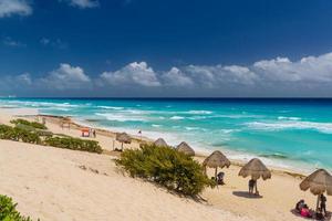 Regenschirme an einem Sandstrand mit azurblauem Wasser an einem sonnigen Tag in der Nähe von Cancun, Mexiko foto