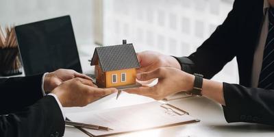 Immobilienmakler-Agent präsentiert und berät den Kunden bei der Entscheidungsfindung, unterzeichnet den Versicherungsvertrag, das Hausmodell, das Hypothekendarlehensangebot für und die Hausversicherung foto