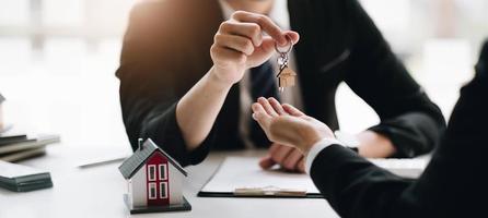 Agenten oder Händler liefern Schlüssel ist das neue Zuhause an einen Kunden, Hypothekengeschäft, Abschluss eines Vertragsabschlusses, Immobilienentwickler. foto