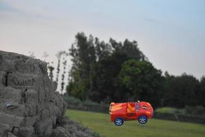 Rotes Autospielzeug fällt vom Hügel foto
