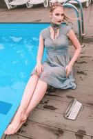 schöne Frau im grauen Cocktailkleid, das fast Swimmingpool legt foto