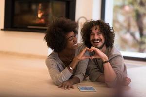 Multiethnisches Paar, das ein Herz mit den Händen auf dem Boden zeigt foto