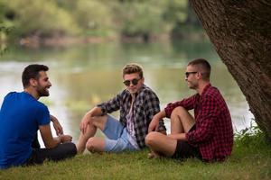 Männer sitzen am Ufer des Flusses foto