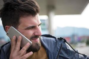 hübscher junger lässiger geschäftsmann mit bart, der handy verwendet foto