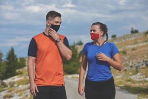 Paar läuft in der Natur mit Maske und macht eine Pause foto