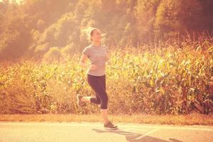 Frau, die entlang einer Landstraße joggt foto