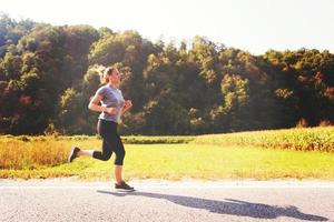 Frau, die entlang einer Landstraße joggt foto