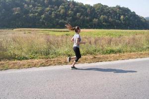Frau, die entlang einer Landstraße joggt foto