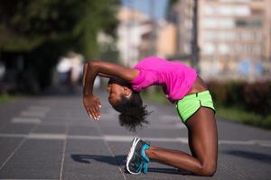 sportliche junge Afroamerikanerin, die sich im Freien ausdehnt foto