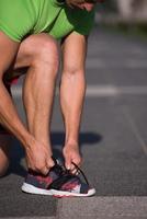 junger athlet, läufer bindet schnürsenkel in schuhen foto