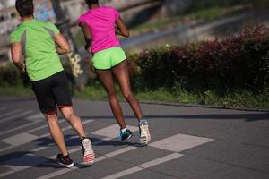 Junges lächelndes multiethnisches Paar, das in der Stadt joggt foto