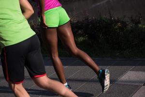 Junges lächelndes multiethnisches Paar, das in der Stadt joggt foto