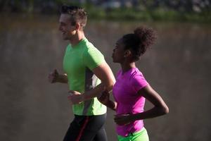 Junges lächelndes multiethnisches Paar, das in der Stadt joggt foto