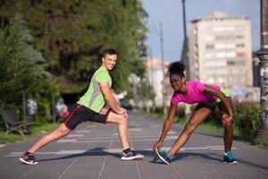 joggendes paar, das sich in der stadt aufwärmt und dehnt foto