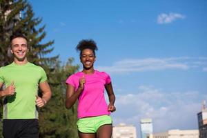 Junges lächelndes multiethnisches Paar, das in der Stadt joggt foto