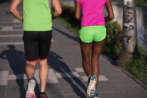 Junges lächelndes multiethnisches Paar, das in der Stadt joggt foto