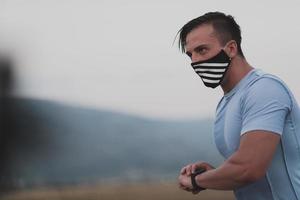 fitness-mann in nasser sportlicher kleidung mit schwarzer gesichtsschutzmaske, die während des ausbruchs des coronavirus im freien in der stadt läuft. covid 19 und körperliche joggingaktivität sport und fitness. neue Normalität foto