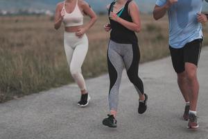drei multiethnische läuferinnengruppen tragen gesichtsmasken und halten soziale distanz im freien. fit gesund vielfältige team tragen sportbekleidung joggen im park auf der natursportstrecke sicherheitsabstand. foto