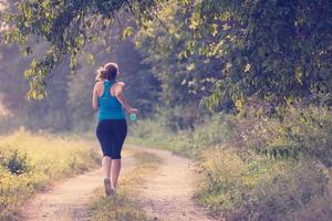 Frau, die entlang einer Landstraße joggt foto