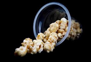 Popcorn in einem Plastikglas ist auf schwarzem Hintergrund isoliert. foto