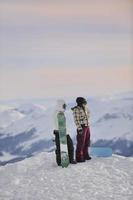 Snowboarderpaar auf dem Gipfel des Berges foto