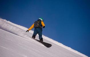 Snowboarder läuft die Piste hinunter und fährt im freien Stil foto