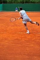 Ein Mann spielt im Freien Tennis foto