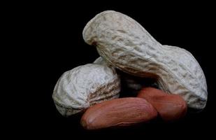 Erdnüsse in der Schale und ohne sie auf schwarzem Hintergrund. foto