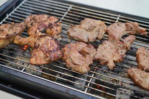 gegrillte Hähnchenschenkel und Schweinefleisch auf dem Holzkohleofen foto