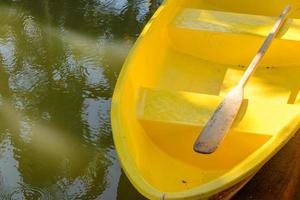 Holzruder auf gelbem Faserruderboot im Teich foto