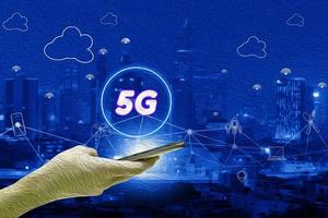 Abstrakte blaue Ölfarbe mit 5g-Netzwerkschnittstelle und Symbolkonzept, Hand, die ein mobiles Smartphone mit strukturiertem Hintergrund des Stadtbildes hält foto