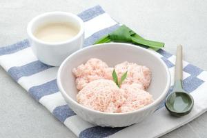 Kue Putu Mayang ist ein traditioneller indonesischer Snack aus zu einer Kugel zusammengerollten Reismehlsträngen, serviert mit Kokosmilch und Palmzucker.
