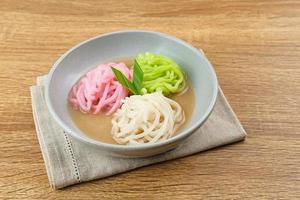 Kue Putu Mayang ist ein traditioneller indonesischer Snack aus zu einer Kugel zusammengerollten Reismehlsträngen, serviert mit Kokosmilch und Palmzucker. ausgewählten Fokus. foto