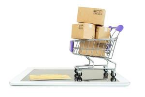 Papierboxen in einem Trolley mit Tablet auf weißem Hintergrund, Online-Shopping oder E-Commerce-Konzept foto