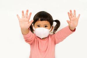 kleines asiatisches mädchen, das maske zum schutz von pm2.5 trägt und handstopp zeigt. luftverschmutzung pm2.5 und coronavirus-konzept foto