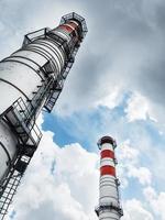 Weiße Schornsteine eines Kraftwerks auf einem Hintergrund von Wolken mit diagonalen Linien foto