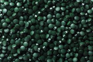 dunkelgrüne runde Tabletten aus Bio-Spirulina als Textur foto