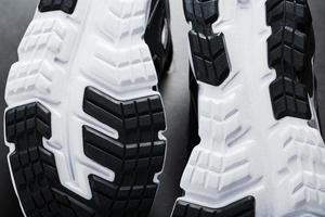 Die schwarz-weiße Sohle von trendigen Sportsneakers ist eine Nahaufnahme im Vollbildmodus. foto