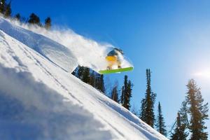 Snowboarder beim Sprung in die hohen Berge am sonnigen Tag. foto