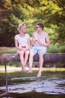 Paar genießt Wassermelone, während es auf der Holzbrücke sitzt foto